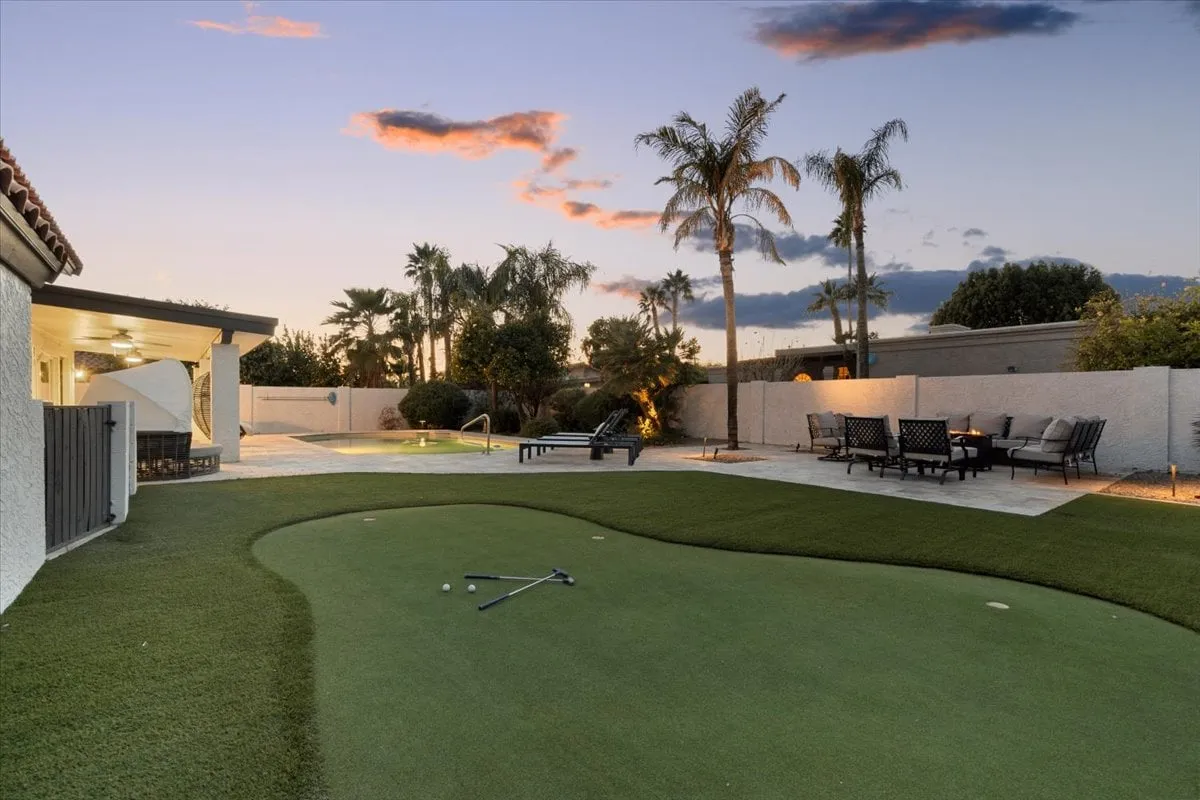 This exterior image features a lush backyard with a putting green, a sparkling swimming pool, lounge chairs, and an inviting outdoor dining area. The scene captures both the recreational (putting green, pool) and social (dining area) aspects described in the section.