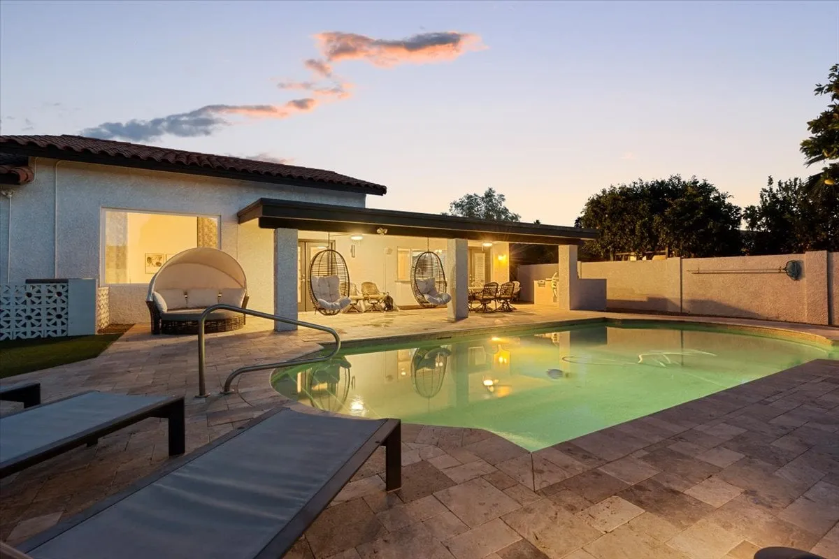 The image features a swimming pool surrounded by comfortable hanging chairs and an outdoor seating area, set against the backdrop of the house exterior. The pool area is stylish and designed for both relaxation and entertaining, with ample room for evening gatherings or poolside brainstorming sessions.