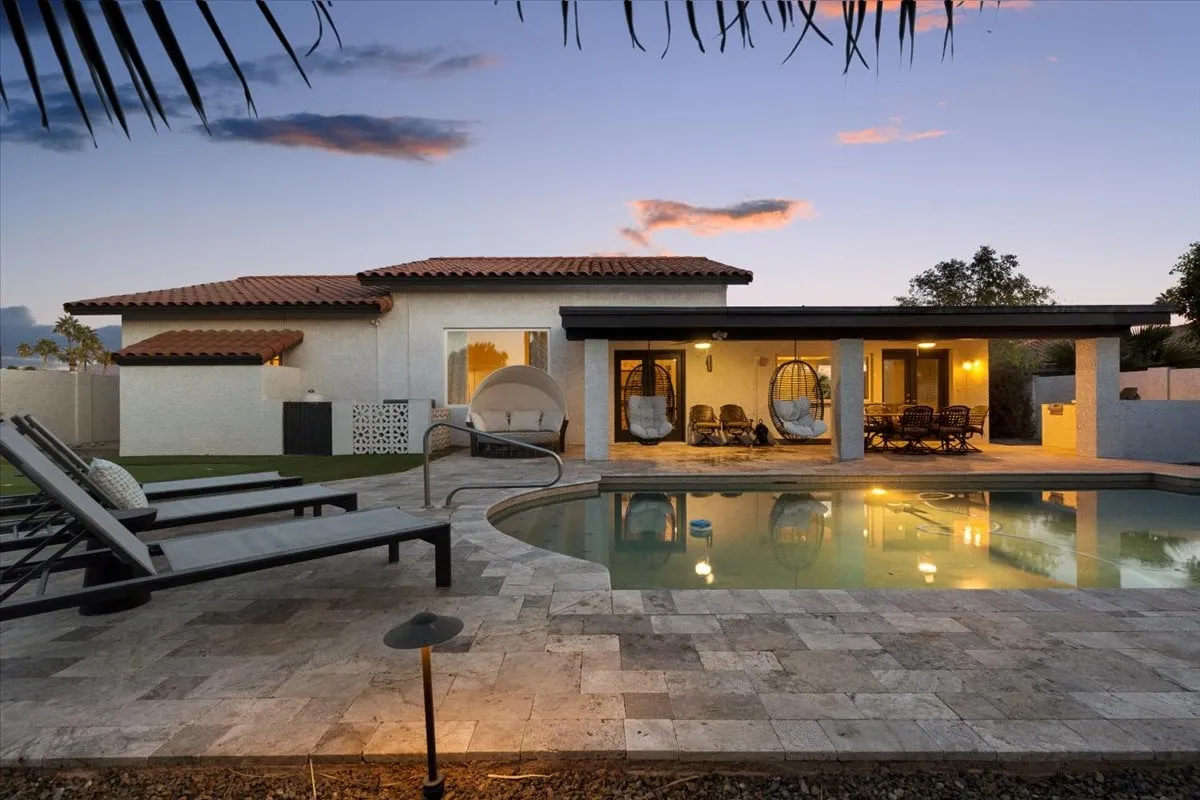 An inviting backyard with a sparkling pool, comfortable outdoor seating, and a hammock set against a tranquil exterior backdrop—an ideal spot for socializing or relaxing after a day out.
